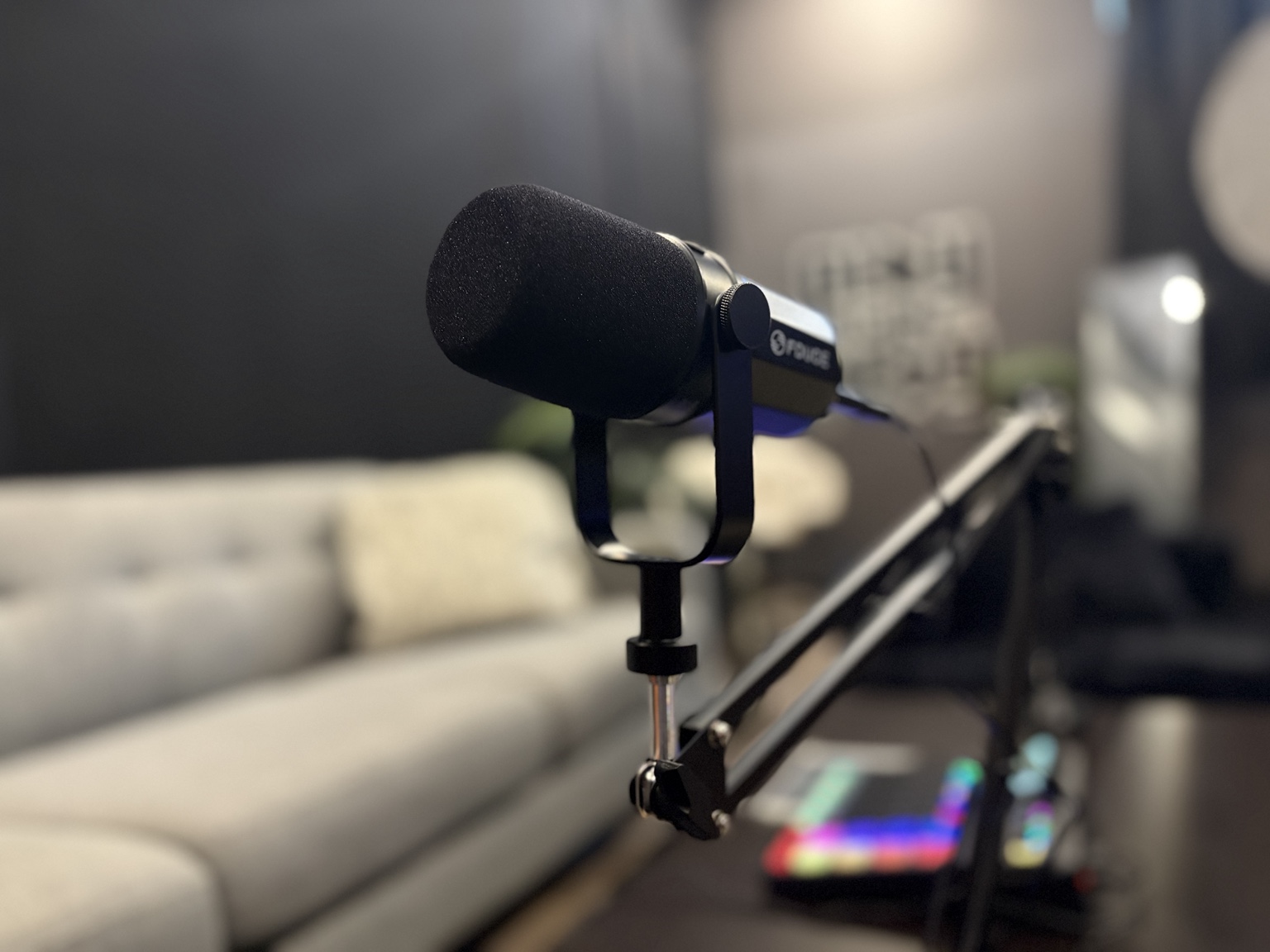 Podcast microphone on a boom arm with the Sound Twist studio set softly blurred behind it