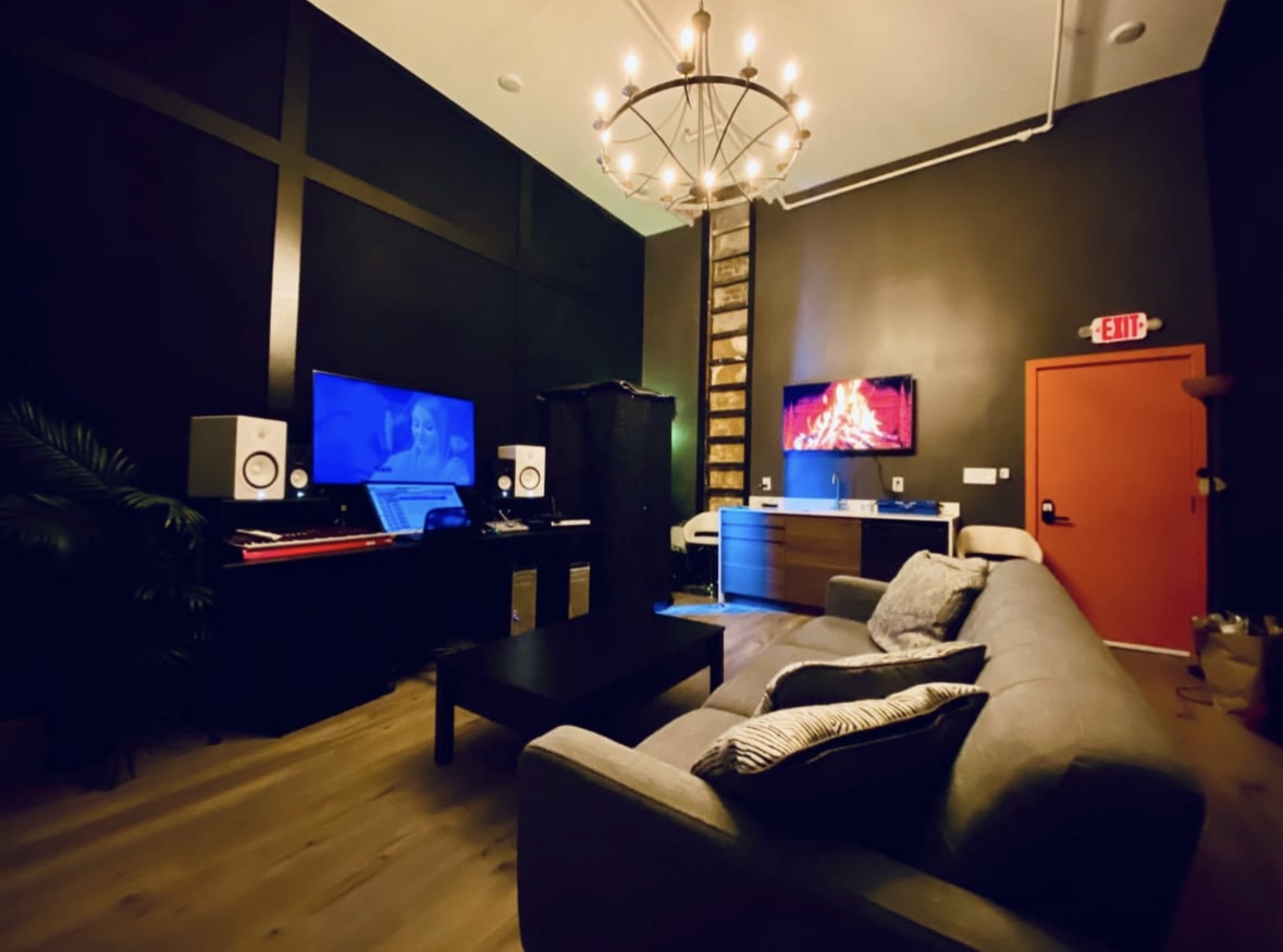 Sound Twist Studios lounge and control area with sofa, workstation, monitors, and chandelier