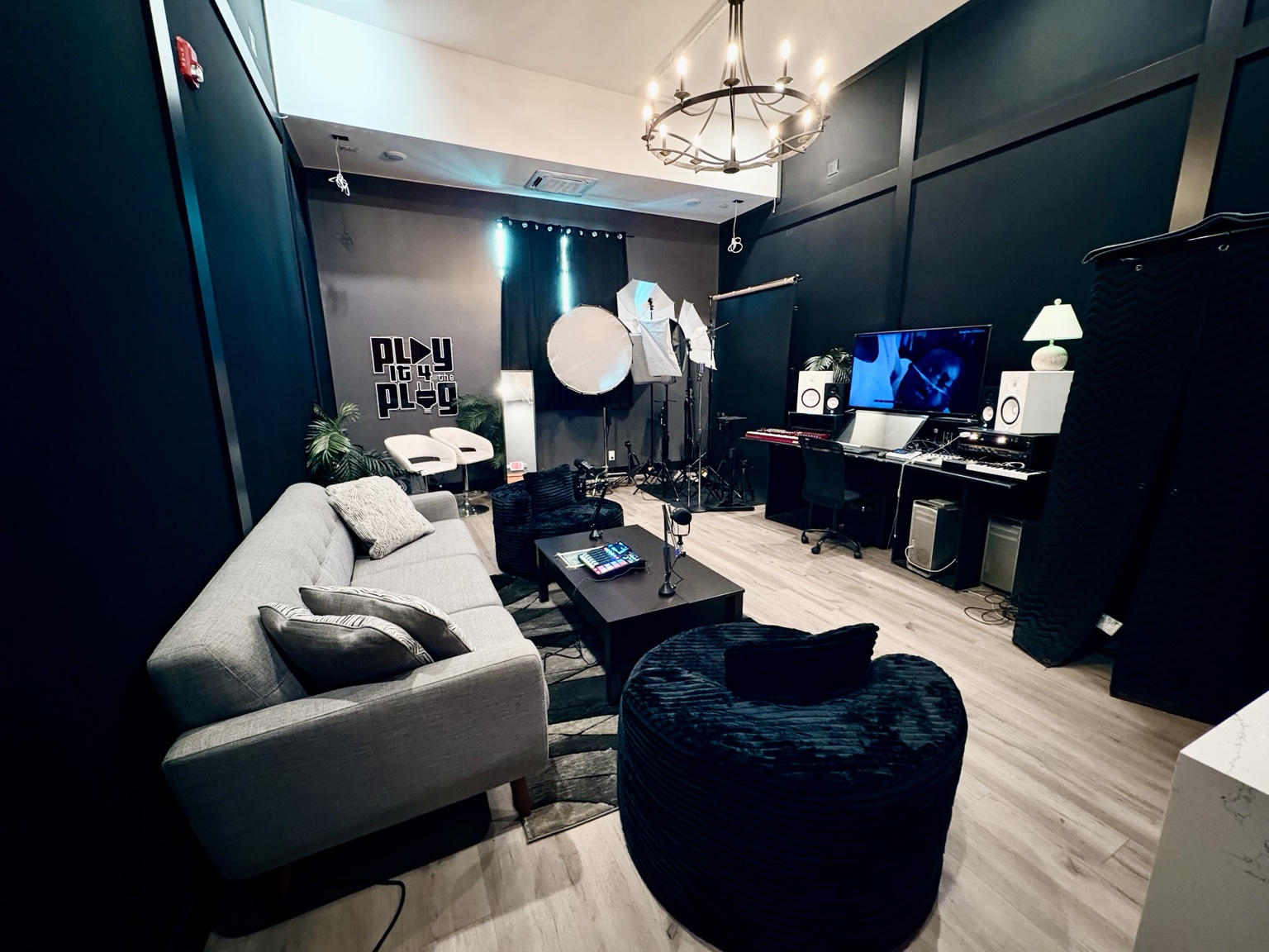 Wide view of Sound Twist Studios with a sofa, production desk, studio monitors, lighting equipment, and podcast setup